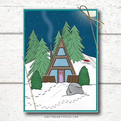 Photo of a non-denominational holiday card boxed set featuring an A-frame cabin nestled against a hill, with evergreen trees surrounding it and the perfect sledding hill in the background