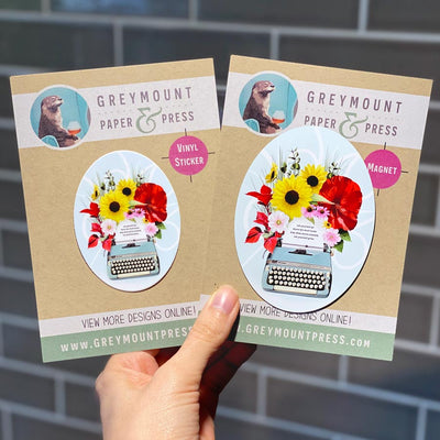 Vinyl sticker with a vintage typewriter with flowers and blooms coming out of the paper. Vintage typewriter laptop sticker with oval shape.